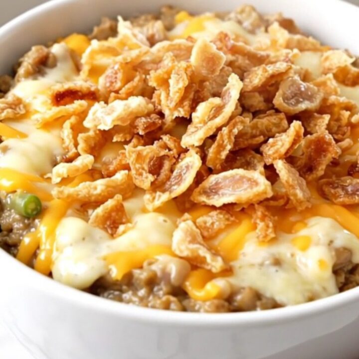 A top-down view of a black slow cooker filled with a creamy green bean and cheese mixture.