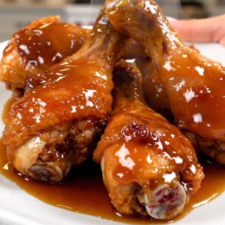 A close-up view of sticky honey garlic chicken drumsticks served on a white plate with a glossy glaze.