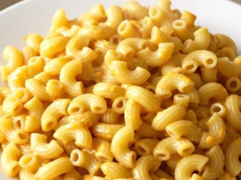 A bowl of creamy pimento cheese macaroni with visible bits of red pimento scattered throughout.