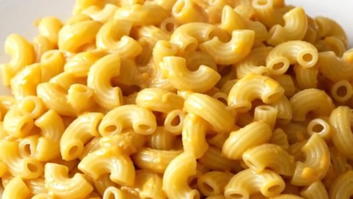 A bowl of creamy pimento cheese macaroni with visible bits of red pimento scattered throughout.