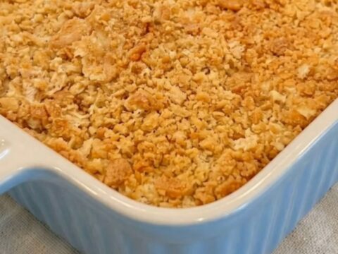 A golden-brown creamy Ritz chicken casserole in a blue ribbed baking dish, sitting on a linen napkin.