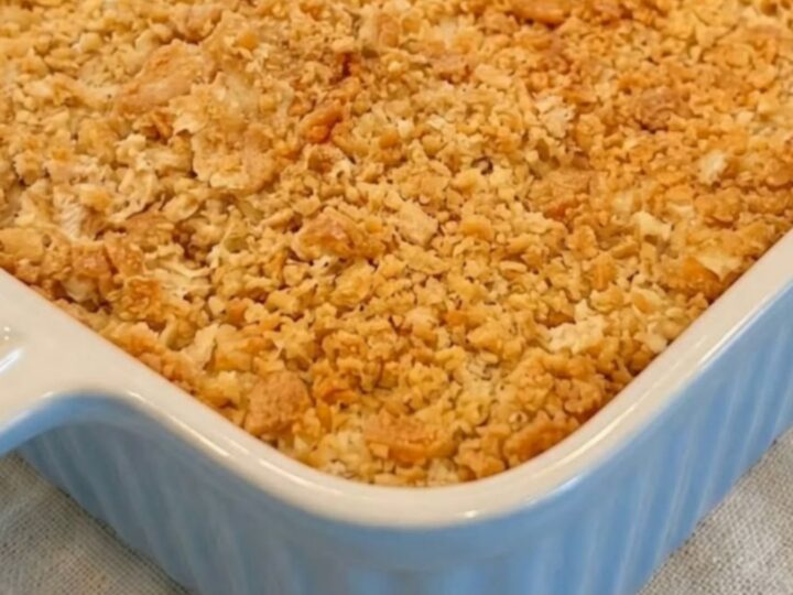 A golden-brown creamy Ritz chicken casserole in a blue ribbed baking dish, sitting on a linen napkin.