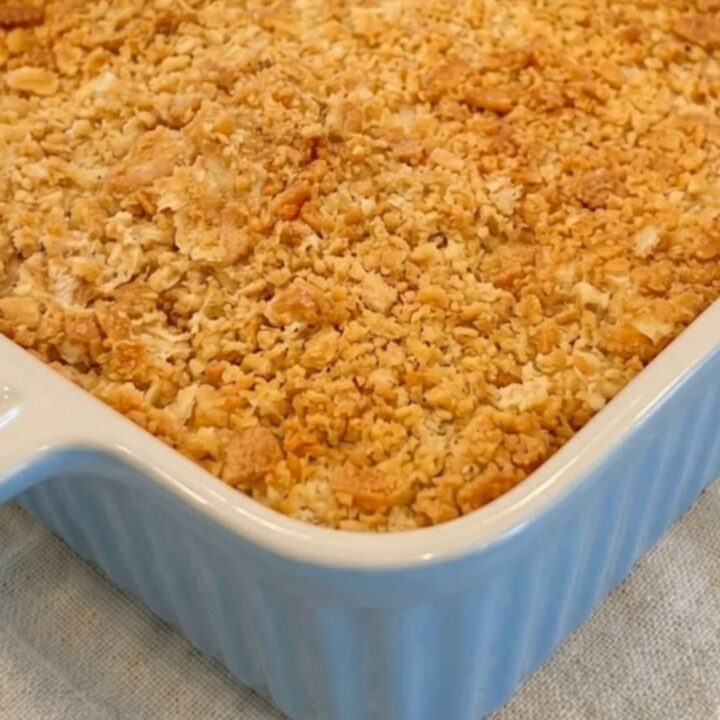 A golden-brown creamy Ritz chicken casserole in a blue ribbed baking dish, sitting on a linen napkin.
