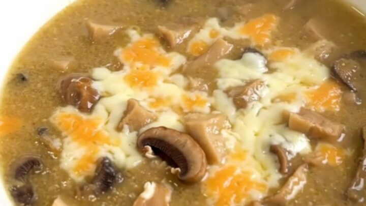 A white bowl filled with creamy wild mushroom chowder, topped with a sprinkle of fresh herbs.