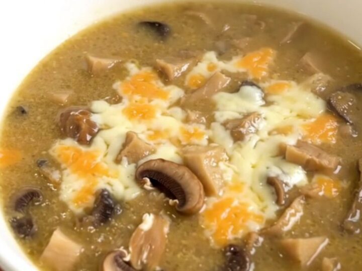 A white bowl filled with creamy wild mushroom chowder, topped with a sprinkle of fresh herbs.