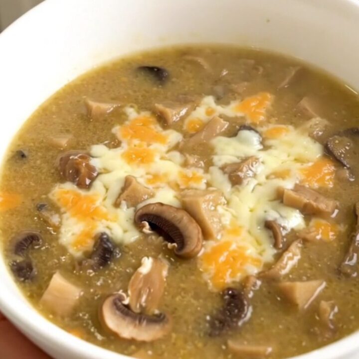 A white bowl filled with creamy wild mushroom chowder, topped with a sprinkle of fresh herbs.