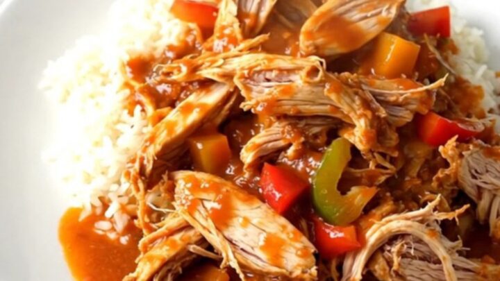 A slow cooker filled with raw chicken breasts, sliced peppers, onions, and crushed tomatoes.