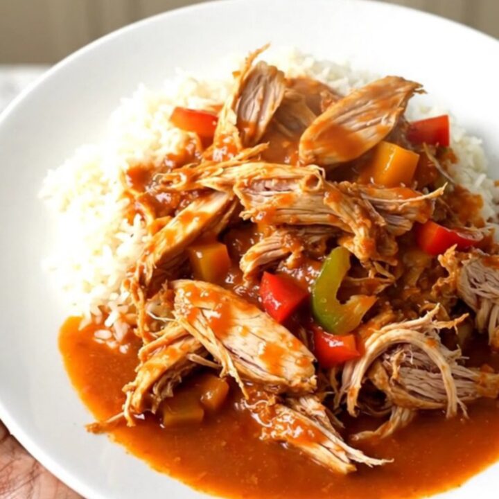 A slow cooker filled with raw chicken breasts, sliced peppers, onions, and crushed tomatoes.
