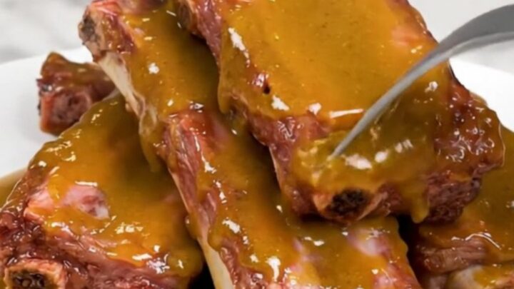 Tender baby back ribs glazed in a golden sauce in a slow cooker.