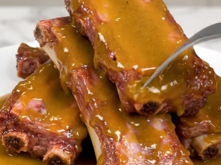 Tender baby back ribs glazed in a golden sauce in a slow cooker.