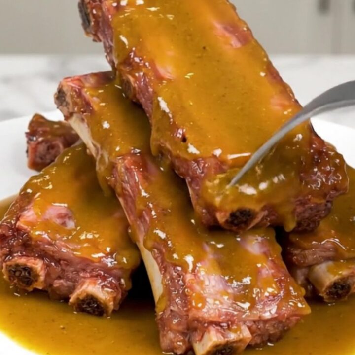 Tender baby back ribs glazed in a golden sauce in a slow cooker.