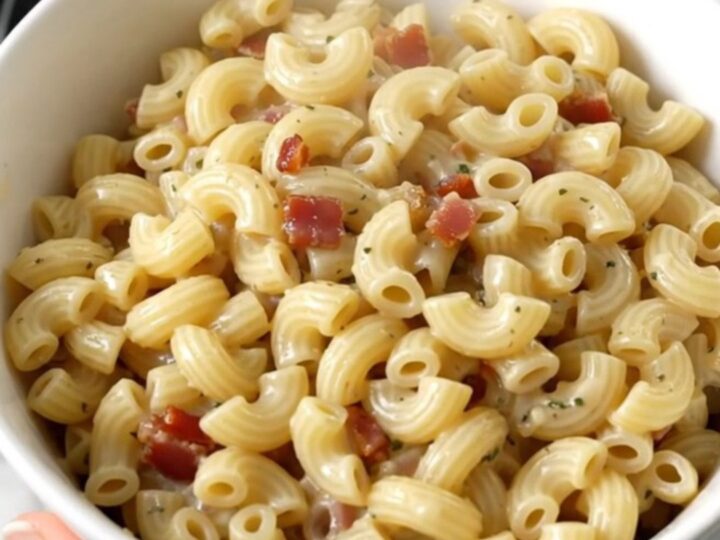 A top-down view of creamy garlic parmesan macaroni with bacon in a slow cooker.