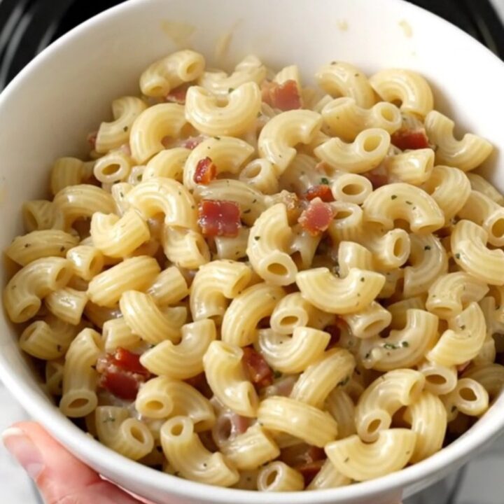 A top-down view of creamy garlic parmesan macaroni with bacon in a slow cooker.