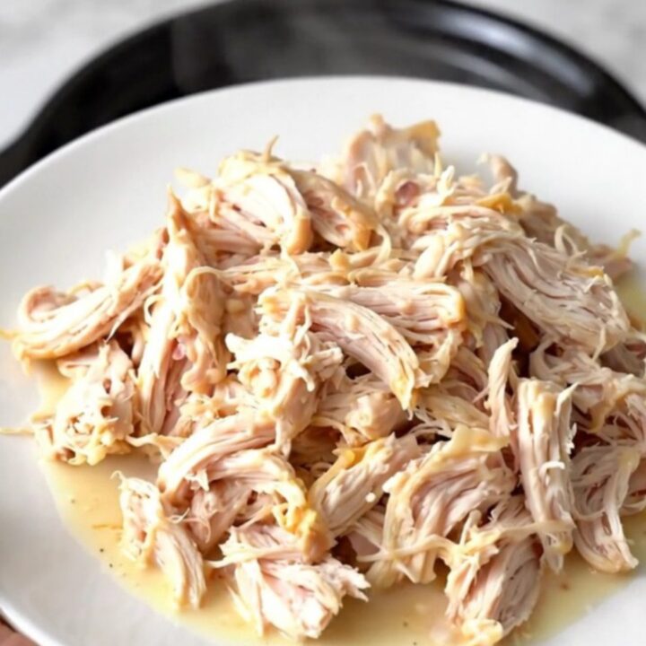 Creamy garlic white cheddar chicken served on a white plate with a steaming sauce.