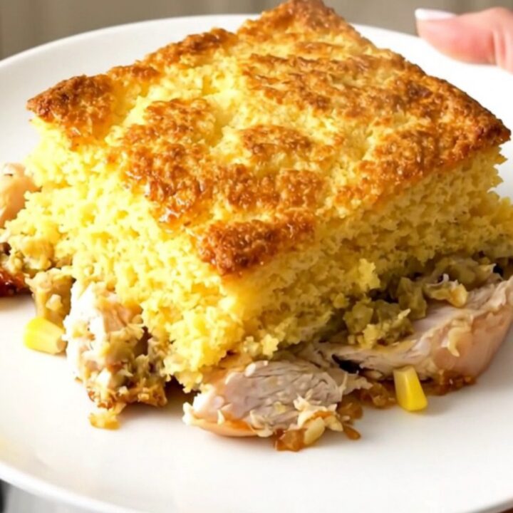 A steaming, golden-topped Crockpot Cheesy Southwestern Cornbread Chicken served in a rustic slow cooker on a bright kitchen