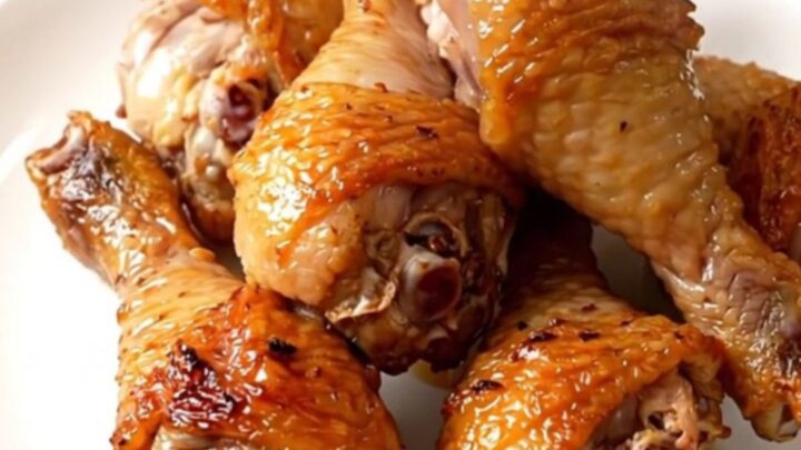 A top-down view of raw chicken drumsticks, diced celery, and ranch seasoning in a slow cooker.