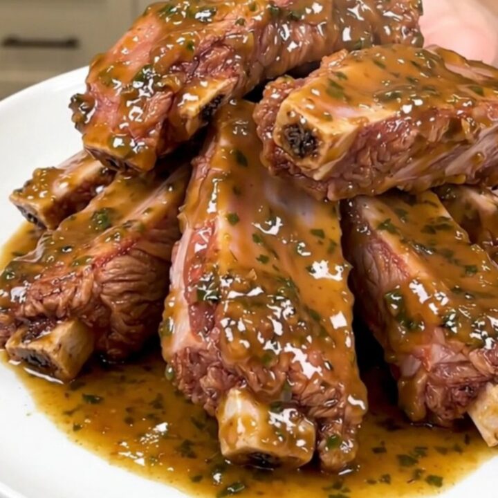 A plate of tender, glossy baby back ribs coated in a rich garlic parmesan sauce.
