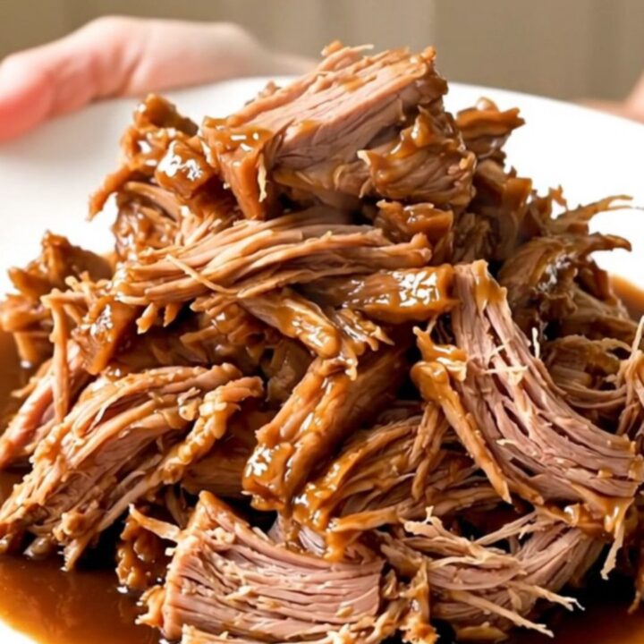 A slow cooker filled with a large, tender pork shoulder roast seasoned with onions and five-spice sauce.