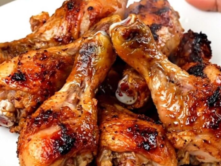 Slow cooker filled with raw chicken drumsticks, red bell peppers, and chipotle sauce.