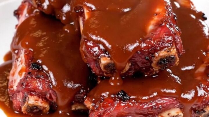 Close-up of succulent barbecue ribs with pineapple glaze on a white plate.