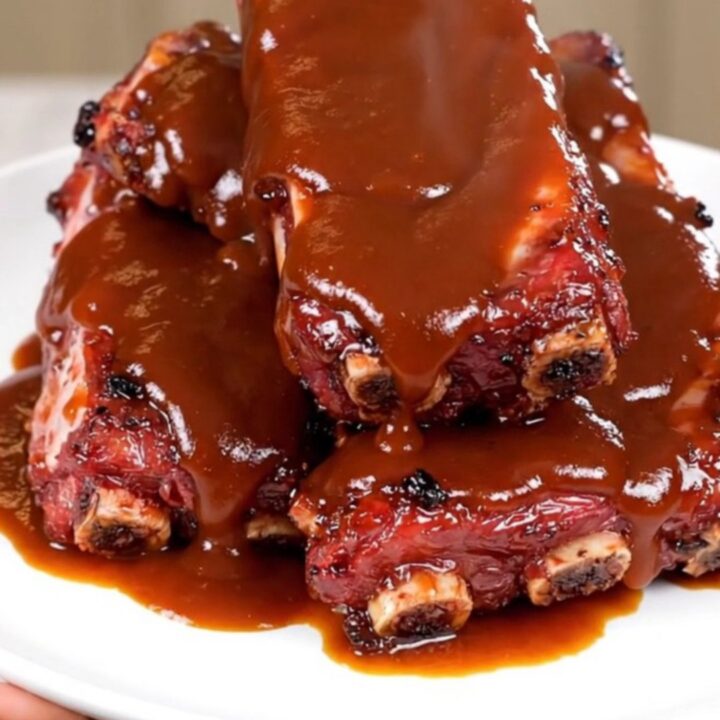Close-up of succulent barbecue ribs with pineapple glaze on a white plate.