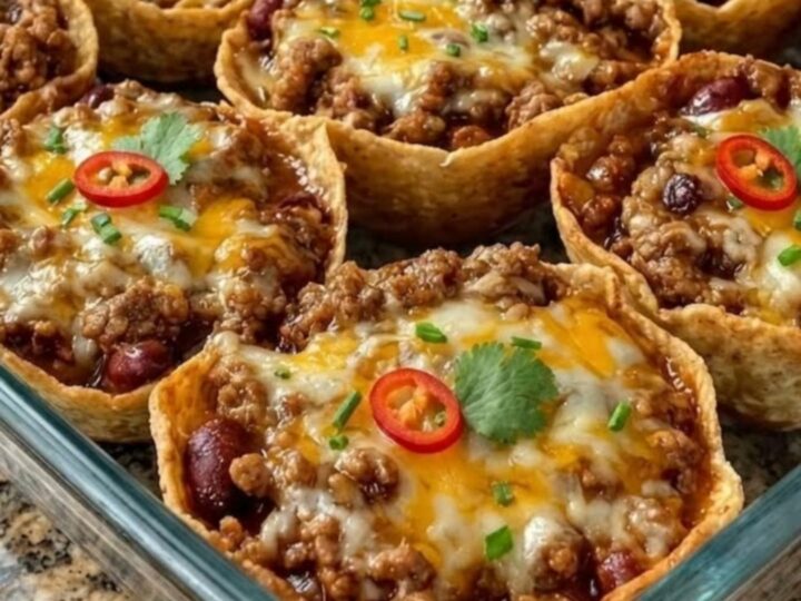 A glass baking dish filled with crispy tortilla cups topped with melted cheese and fresh herbs.