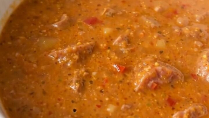 A steaming bowl of creamy sausage and roasted red pepper chowder served in a white bowl.