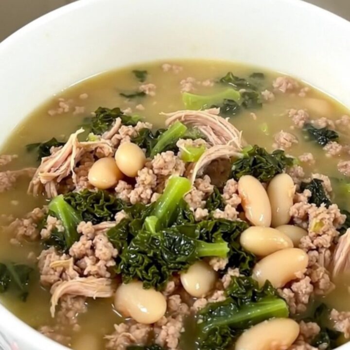 A steaming bowl of slow cooker ground turkey and white bean soup with kale, served in a white bowl.