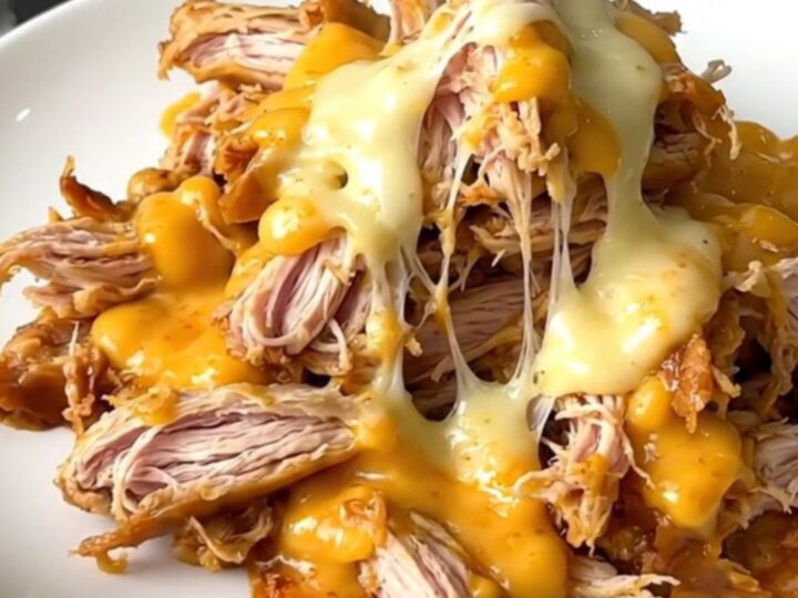 A slow cooker filled with creamy shredded chicken, topped with green pickled jalapenos and a rich sauce.