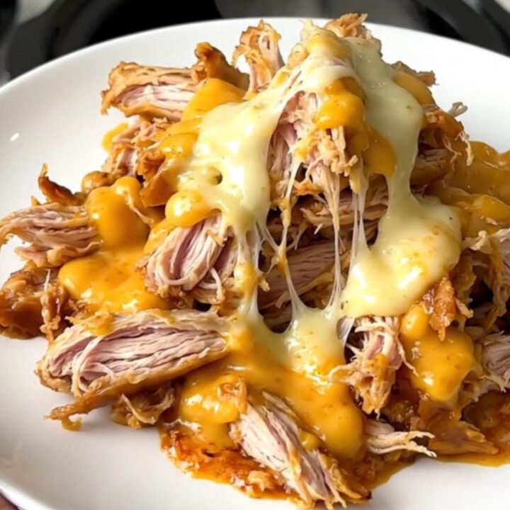 A slow cooker filled with creamy shredded chicken, topped with green pickled jalapenos and a rich sauce.