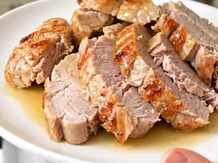 A plate of sliced, tender pork tenderloin drizzled with savory pan juices and sun-dried tomatoes.