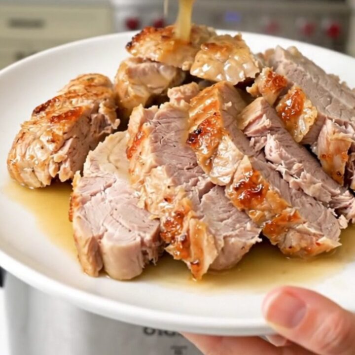 A plate of sliced, tender pork tenderloin drizzled with savory pan juices and sun-dried tomatoes.