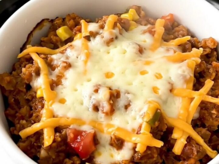 A top-down view of a slow cooker filled with raw ground turkey, black beans, and salsa.