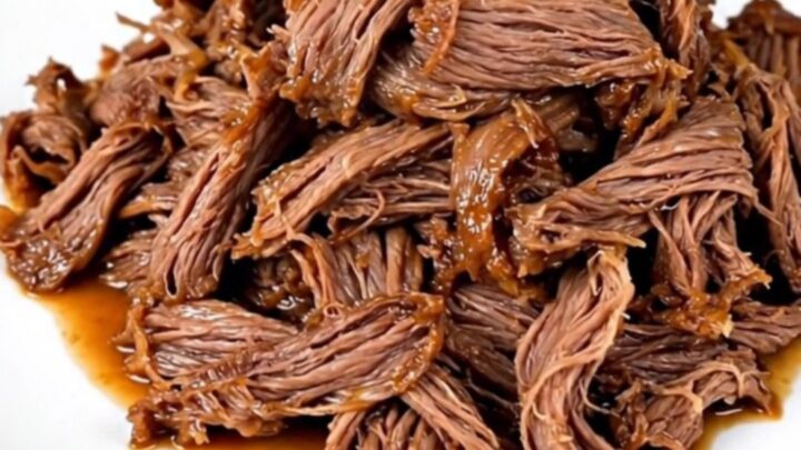 A close-up of tender, glossy mango habanero shredded beef served on a white plate.