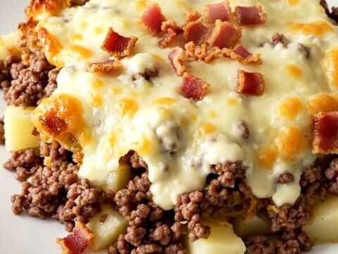 A steaming crockpot casserole with ground beef, potatoes, and melted Swiss cheese in a slow cooker.