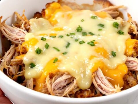 A white bowl filled with creamy shredded chicken and tender cauliflower florets in a rich, glossy sauce.