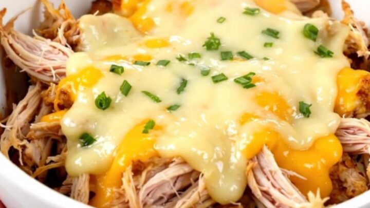 A white bowl filled with creamy shredded chicken and tender cauliflower florets in a rich, glossy sauce.