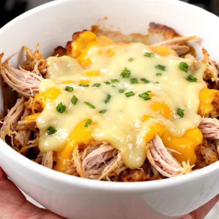 A white bowl filled with creamy shredded chicken and tender cauliflower florets in a rich, glossy sauce.