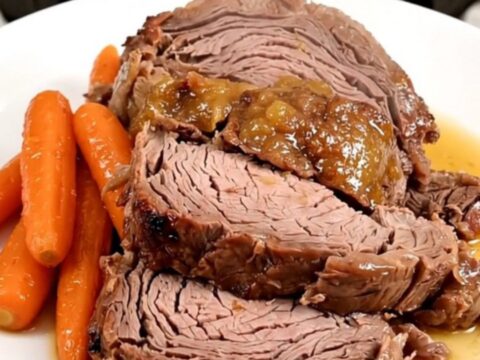 A slow cooker filled with a tender beef chuck roast, glazed baby carrots, and an apricot Dijon sauce.