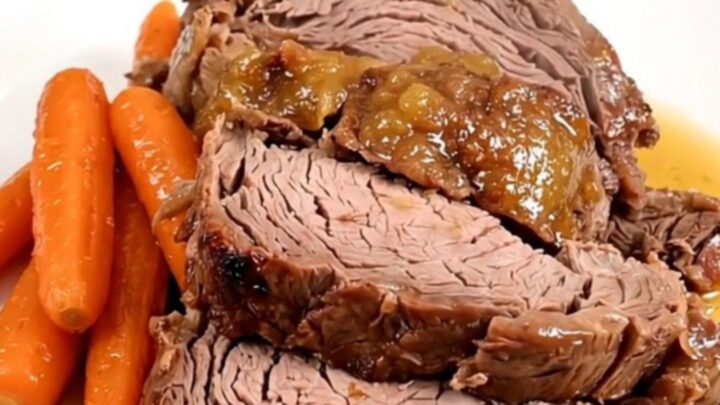 A slow cooker filled with a tender beef chuck roast, glazed baby carrots, and an apricot Dijon sauce.