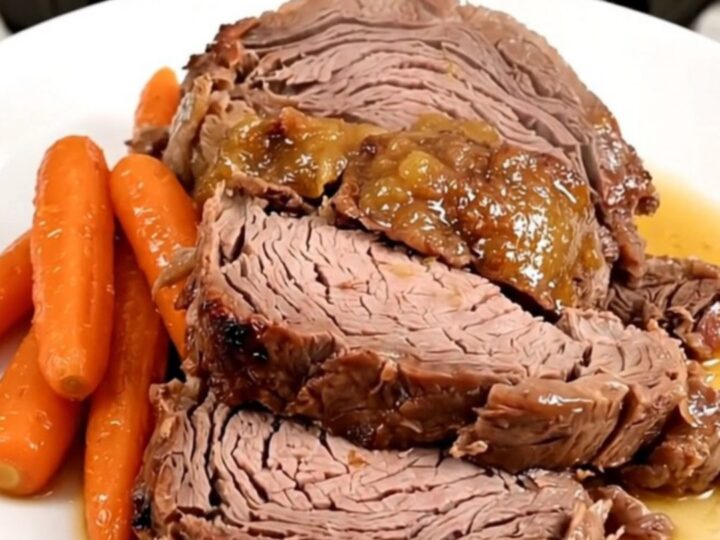 A slow cooker filled with a tender beef chuck roast, glazed baby carrots, and an apricot Dijon sauce.