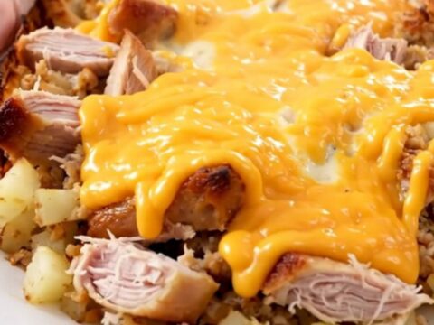 A steaming, cheesy ground turkey and potato casserole served on a white round plate.