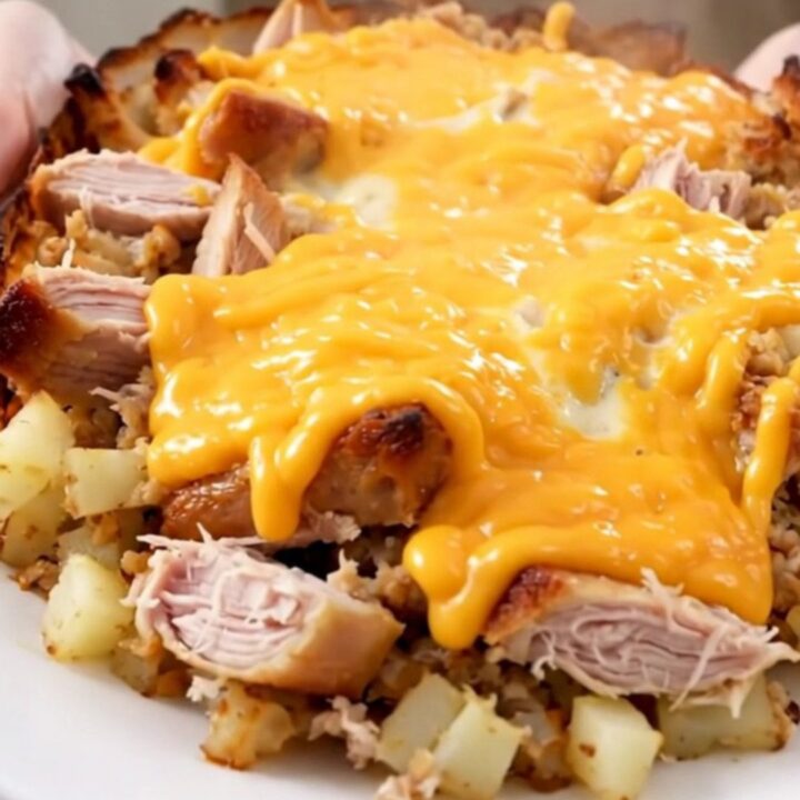 A steaming, cheesy ground turkey and potato casserole served on a white round plate.