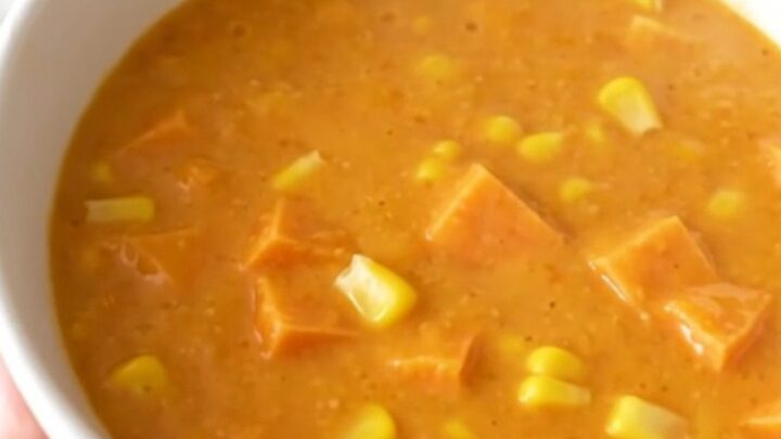 A close-up of a creamy sweet potato and corn chowder in a white bowl with steam rising.