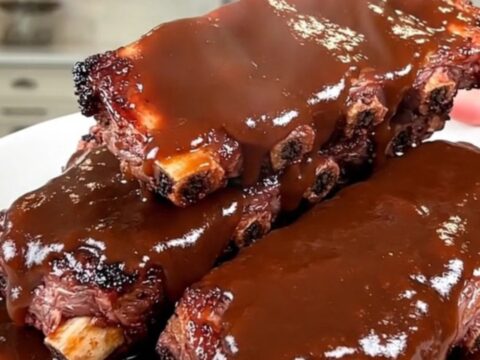 Slow cooker coffee rubbed barbecue baby back ribs arranged on a white serving plate.