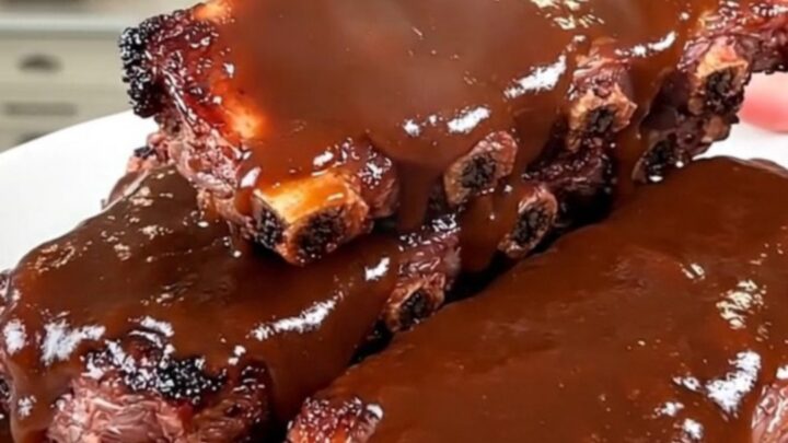 Slow cooker coffee rubbed barbecue baby back ribs arranged on a white serving plate.