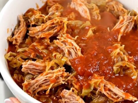 A white bowl filled with steaming ground turkey and cabbage casserole against a cream kitchen background.