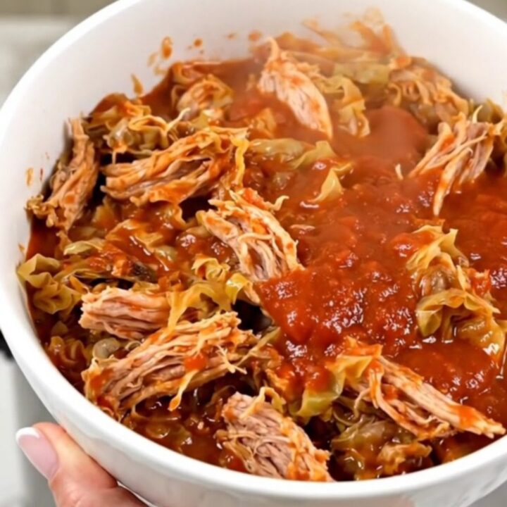 A white bowl filled with steaming ground turkey and cabbage casserole against a cream kitchen background.