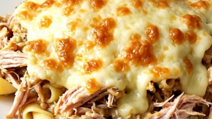 Creamy slow cooker alfredo chicken with melted mozzarella on a white plate.