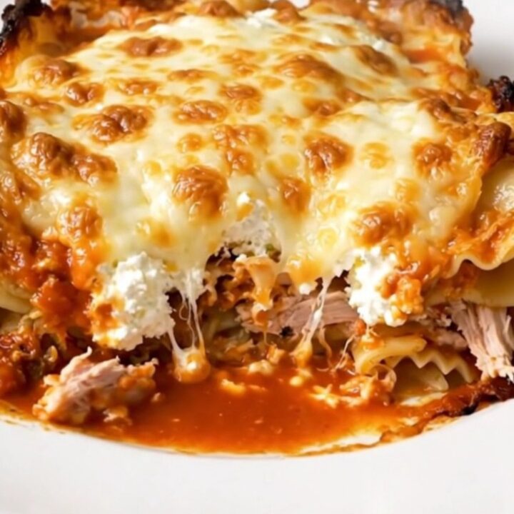 A steaming, glossy ground turkey lasagna casserole served on a white plate.